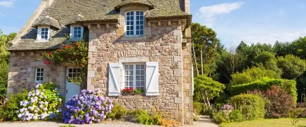 Acheter dans l’immobilier – une maison ancienne en pierre arborée et fleurie