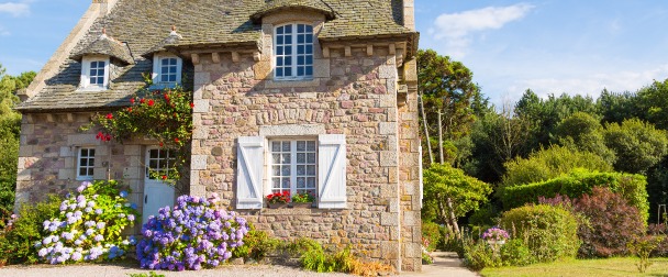 Acheter dans l’immobilier – une maison ancienne en pierre arborée et fleurie