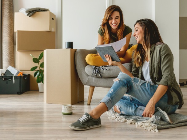 Louer un appartement – deux amies en plein emménagement discutant dans leur nouveau logement