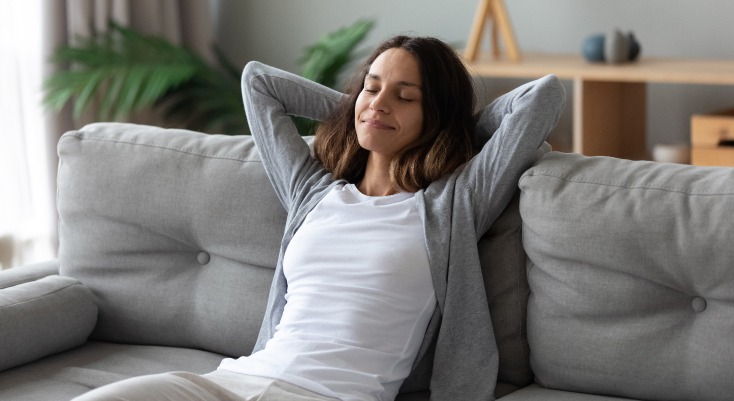 Vendre bien immobilier – une jeune femme détendue dans son canapé
